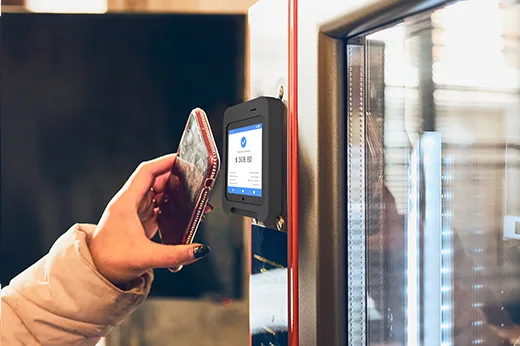 Customer tapping a phone on a smart payment terminal fitted to a vending machine